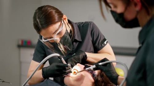 Dental Office Girl Dentist Doing Cleaning to Young Guy Before the Whitening Procedure