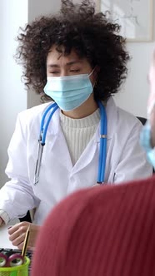 Doctor and Patient in Face Mask Talking in a Medical Consultation in a Clinic