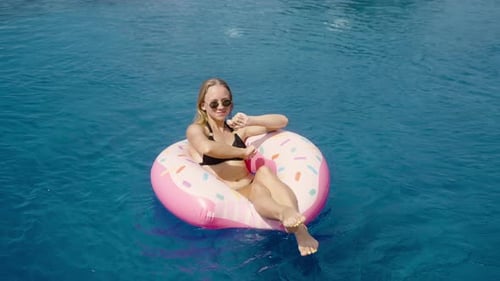 Woman Relaxing on Donut Float in Swimming Pool