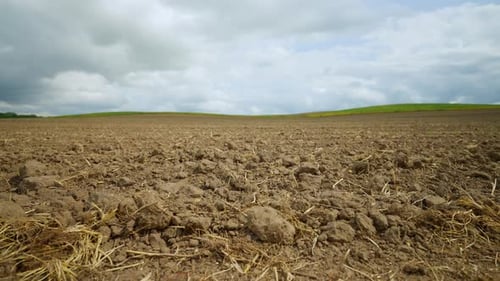 Gepflügtes Ackerfeld unter bewölktem Himmel Brauner Boden eines gepflügten Feldes mit Strohresten