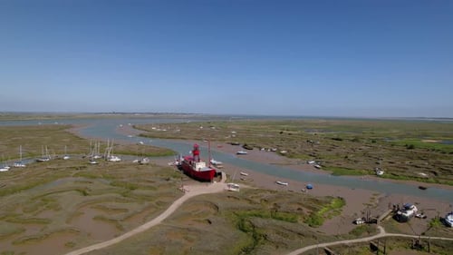 Aerial view around a Lightship stuck during the low tide, sunny Tollesbury, UK - orbit, drone shot