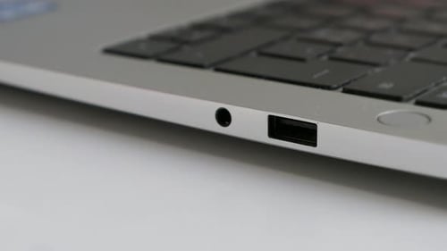 Hand plugging black HDMI cable into laptop, close up