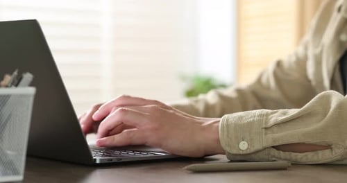 Mann arbeitet am Laptop am Holzschreibtisch im Büro, Nahaufnahme