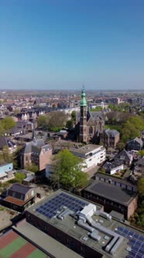 Aerial view of a Dutch town with a prominent church in the center, surrounded by residential homes