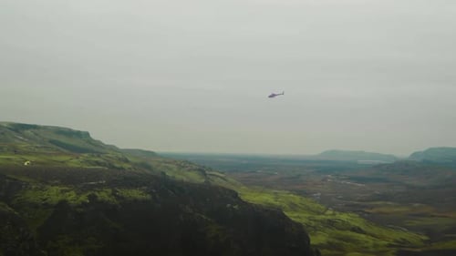 Helicopter Flies over Green Mountains Landscape