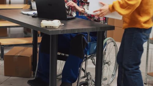 Man with Chronic Disability Using Laptop in Warehouse