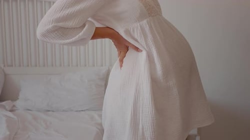 Side view of young pregnant woman back muscles hurting.