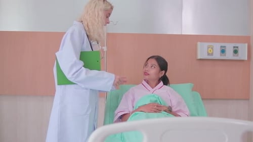 A female doctor visits an Asian patient woman in a hospital.