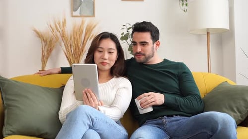 Happy Couple Relaxing At Home Using a Tablet