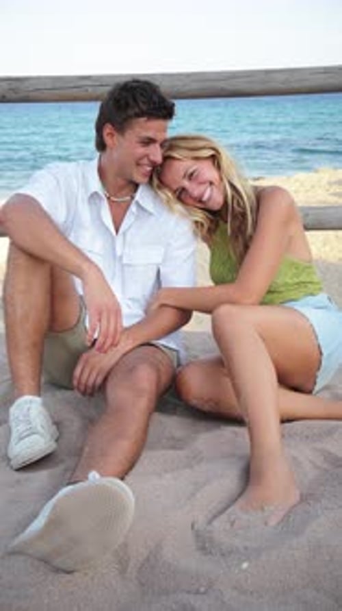 Joyful Couple Relaxing Together on a Sandy Beach During a Sunny Day Enjoying Their Carefree Vacation