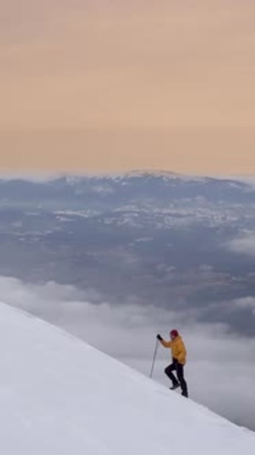 Climber Ascends Snowy Mountain Peak at Sunrise