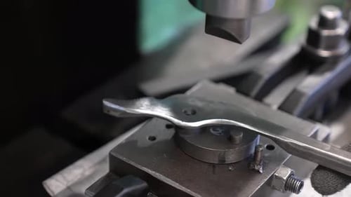 Vue rapprochée d'une pince en acier forgé maintenue dans un gabarit d'assemblage de précision avec rivet pivotant