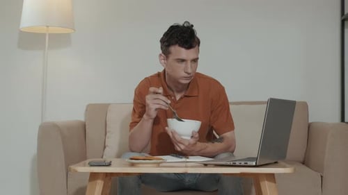 Young Home Office Manager Watching Online Video by Lunch