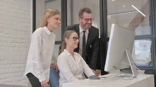Three Colleagues Working Together at Computer in Office