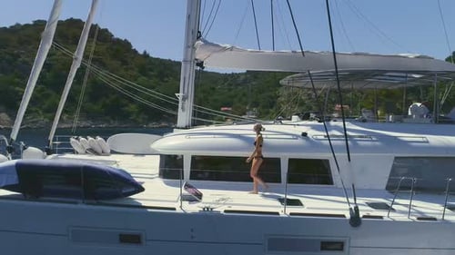 Nach der Luftaufnahme einer Dame, die auf dem weißen Segelyachtdeck spaziert und sich ihren Freundinnen anschließt