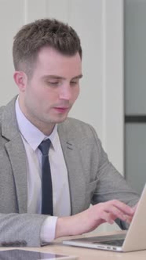 Focused Man Types on Laptop at Desk
