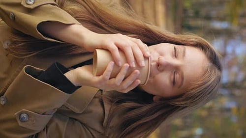 Woman Enjoys Warm Drink Outdoors on Autumn Day