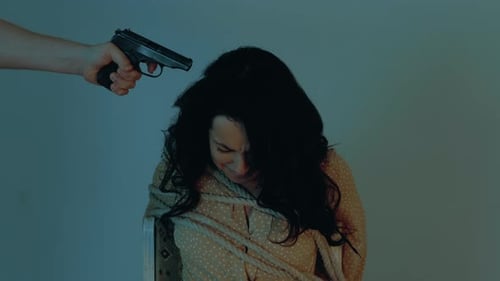 Un kidnappeur a pointé une arme sur la tempe de la femme otage assise sur une chaise et attachée avec une corde