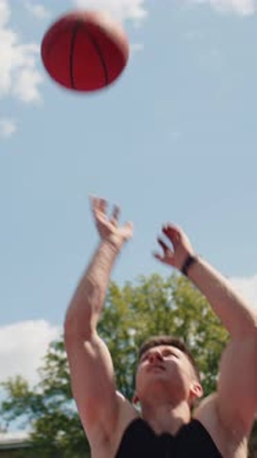 Athletic Man in Sportswear Playing Basketball Game Successfully Throws Ball Into the Basket Ring