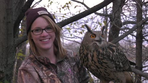 Woman Smiling Holding an Owl in Forest
