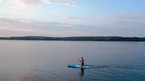 Man Paddleboarding on Lake in Summer