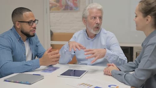 Old Businessman Talking with Mixed Race Business People in Meeting