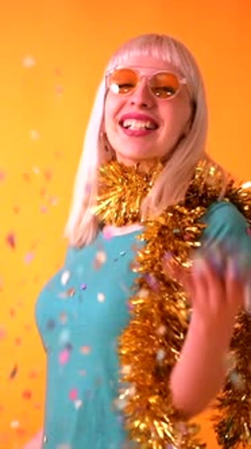 Confetti party at a celebration, blonde caucasian girl in studio on yellow background