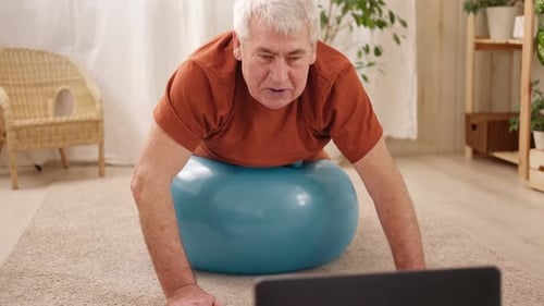 Mature Senior Man Doing Fitness Exercises Gymnastics at Home Online Lesson with Laptop Pc Talking