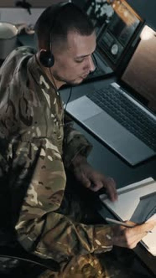 Vertical of Operator in Camouflage Uniform Transmitting Data in Command Center