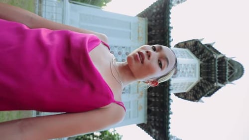 Woman Poses in Pink Dress Against Unique Building