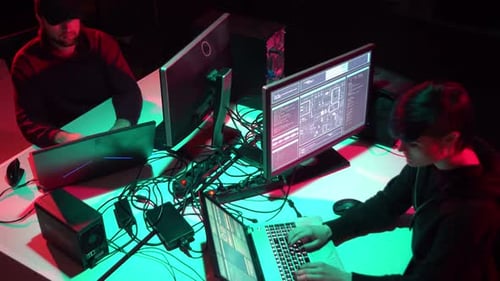 Coding Workstation: Two People Typing on Laptops