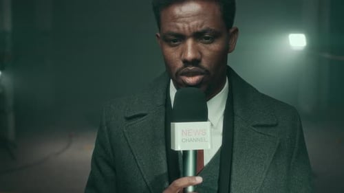 News Reporter Speaking Into Microphone in Dark Studio