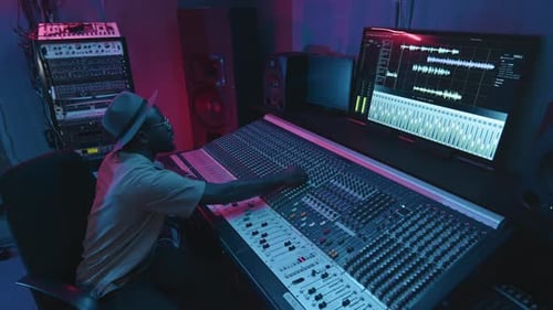 Young Sound Engineer Looking at Screen with Settings and Leveling Consoles
