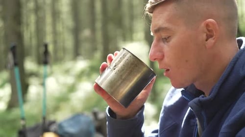 Young Adult Drinking Hot Beverage in Forest