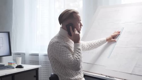Un architecte concentré travaille dans un loft à l'aide d'une planche à dessin sur le lieu de travail d'un jeune ingénieur moderne