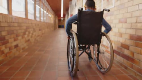 Student in wheelchair moving through school hallway with brick walls