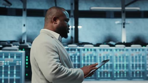 Technician Working in High Tech Server Hub Analyzing Data on Tablet