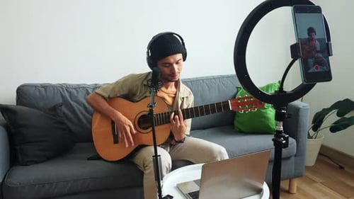 Young Man Plays Guitar and Sings at Home