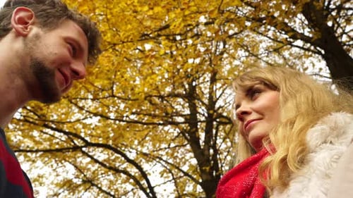 Couple Kissing In Autumn Park Behind Leaf