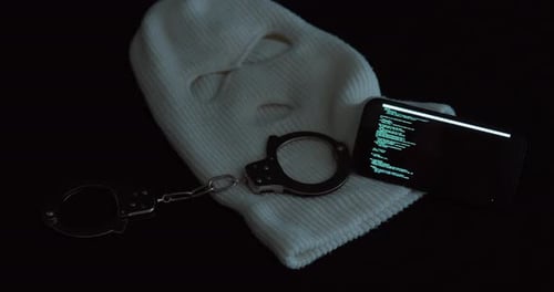 Ski Mask, Handcuffs and Phone Hacking in Dark Lighting