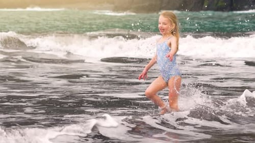 Joyful child running through waves at the beach during a sunny summer vacation