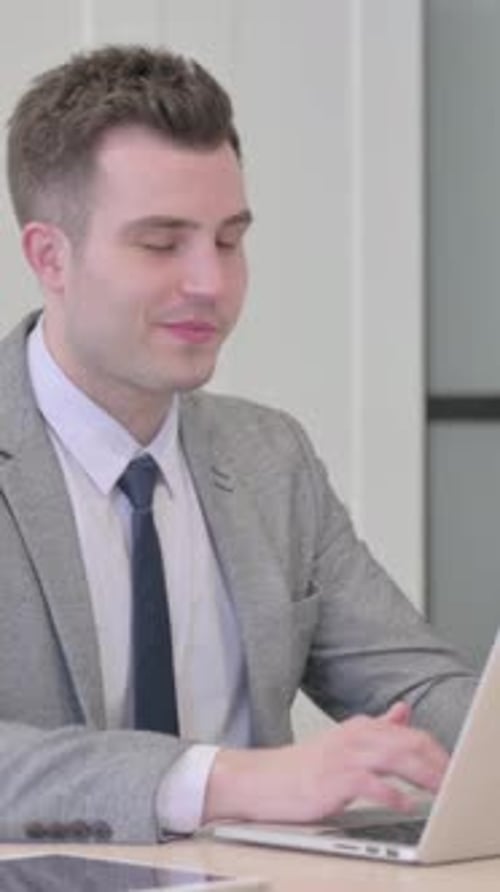Well-dressed Man Video Calling on Laptop in Office