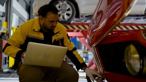 Mechanic Asian man using computer laptop examining fixing repairing front car engine automobile