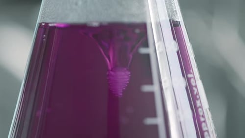 Blick in ein Labor, das Tests mit einer rosafarbenen Flüssigkeit in der Flasche durchführt
