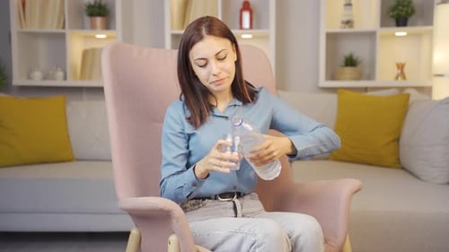 The sick young woman drinks a lot of water.