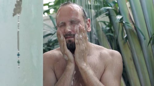 Man Cleanses Face in Refreshing Tropical Shower