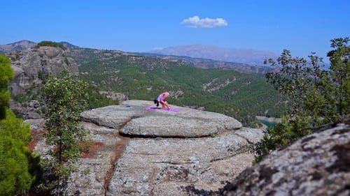 Wide Shot of Woman Practicing Yoga on Cliff with Mountain Landscape