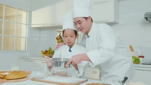 Child and Adult Baking Together in Bright Kitchen