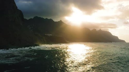 Mountain Sunset Sunbeams Break Through Clouds and Illuminate Ocean Wave Scenic Seascape