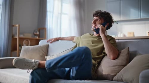 Young Man Relaxing, Talking on Phone at Home